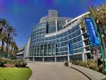 A curved, glassy building in bright sunlight, with a blue sky...with weird purple and green mottling in the sky.