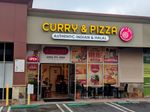 Storefront in a strip mall. A sign proclaims Curry & Pizza. Below it the doors stand wide open.