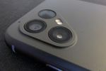Back of a smartphone, gray plastic with a rounded triangle in one corner. Three circles, two of them clearly camera lenses and the third dark, fill the triangle's corners, and a small LED light fits between the circles on the longer side.