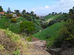 Looking along a narrow valley between rolling green hills fitted with trees and a few houses