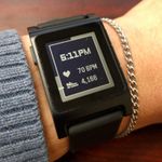 The same digital watch, this time showing 5:11 PM, a heart icon with 70 BPM, and a shoe icon with 4,166. The display border is black around the upper left corner and checkered around the rest, with a solid line marked through the left edge of the checkered part.