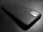 A black and white view of the back of a smartphone, angled so that its shadow falls toward us. There's a G at one end, a depressed circle near the other, and a rounded glass square in one of the corners that hints a camera lenses behind it.