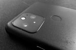 Back of a smartphone, gray plastic with a depressed circle in the middle. A rounded glass square sits in one corner, with two camera lenses, an LED and another sensor looking sort of like the Southern Cross constellation.