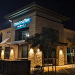 Nighttime view of a low, squarish building with a lit up white sign saying Rival Coffee Co.